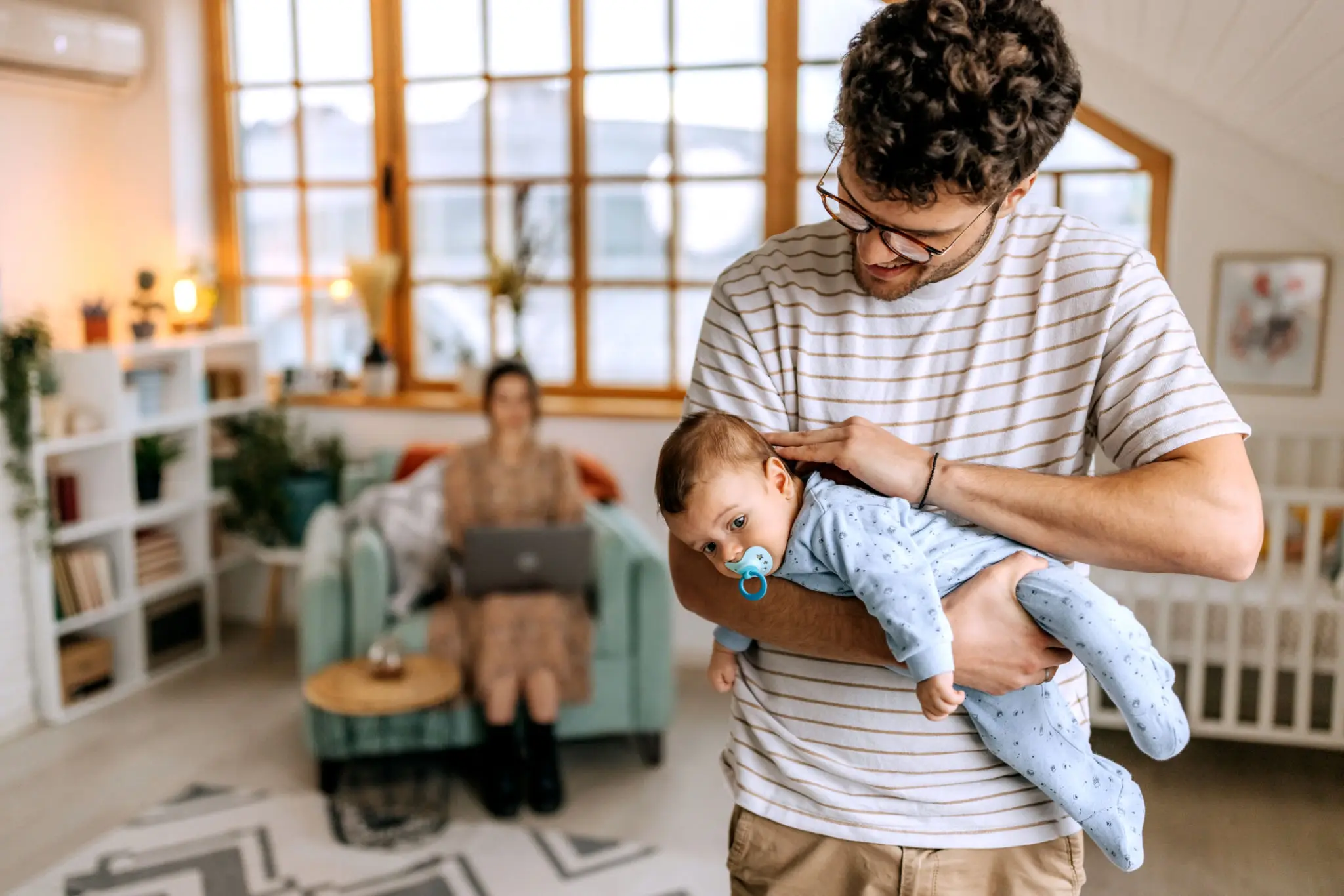 Father holding baby with pacifier at home
