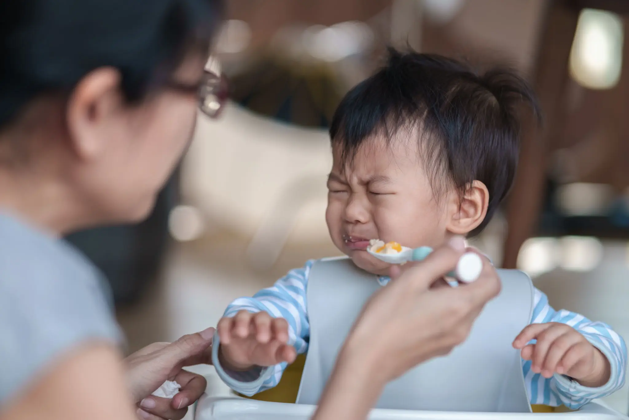 Crying toddler refusing spoonful of food