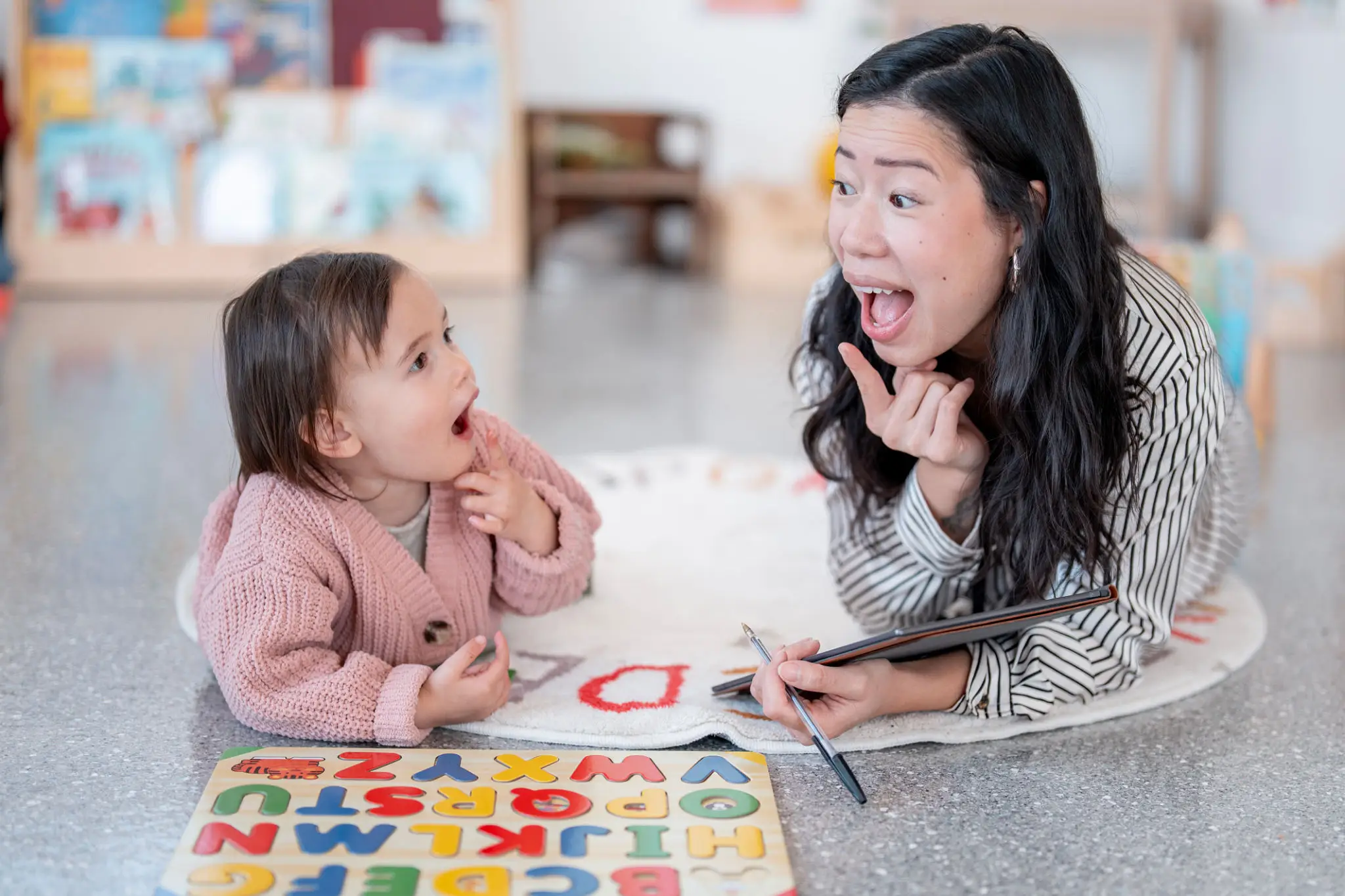 Woman and toddler playing with alphabet puzzle
