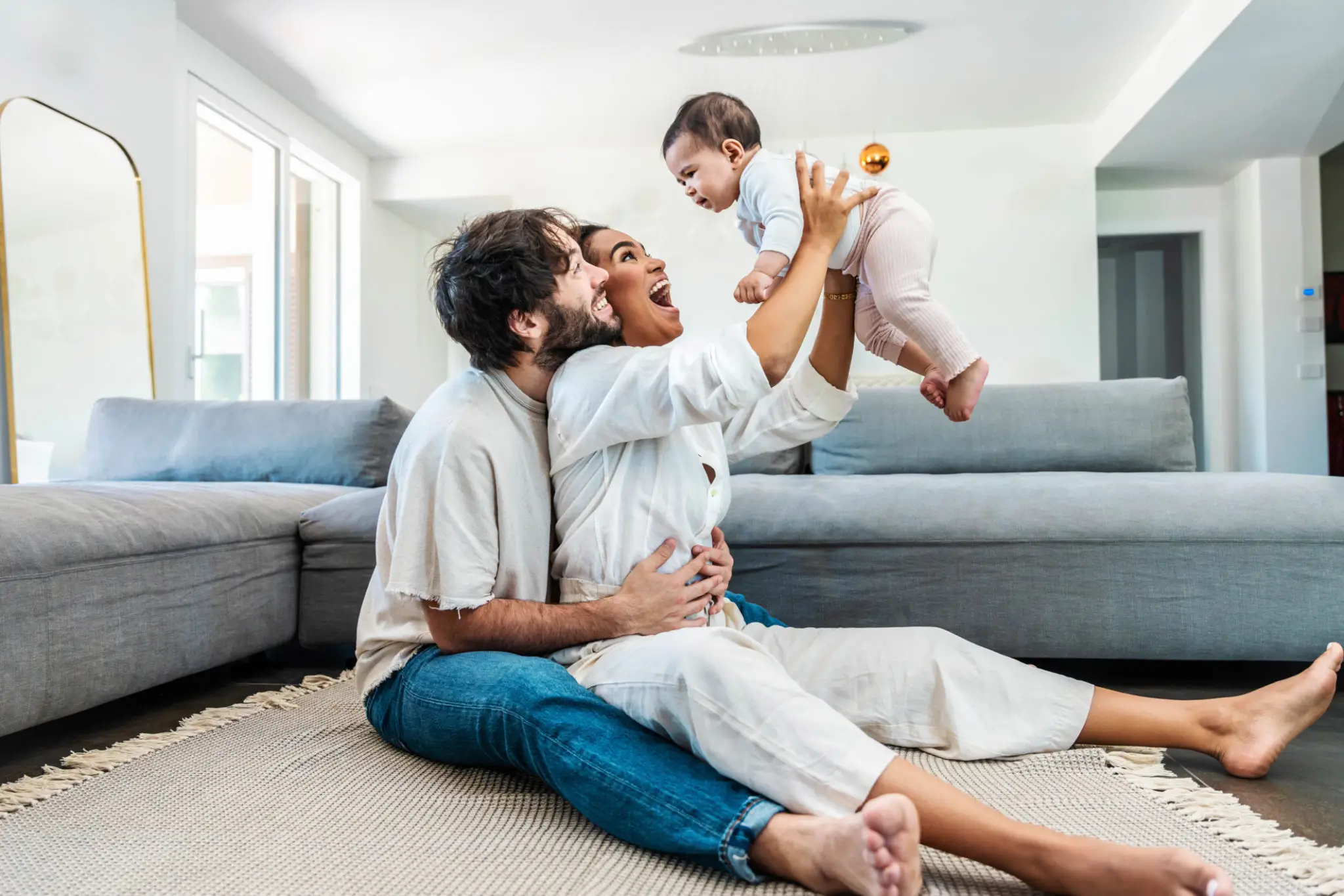 Happy parents playing with baby on rug